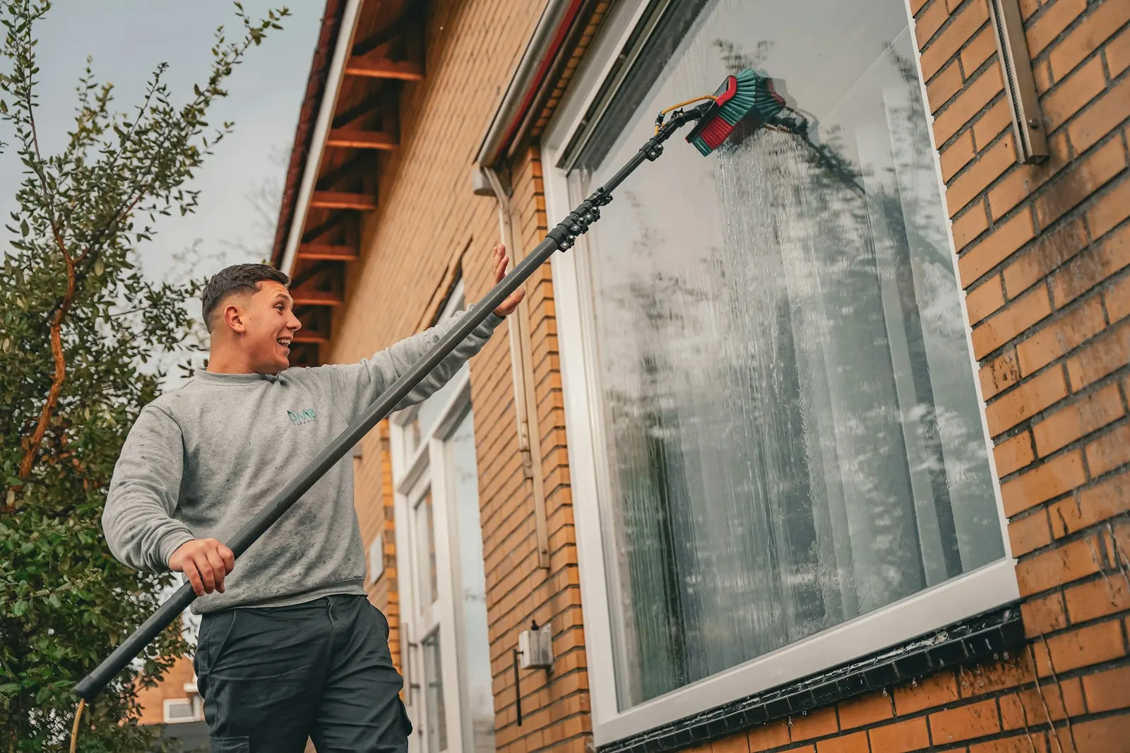 Fensterreinigung mit Teleskopstange an einem Wohnhaus