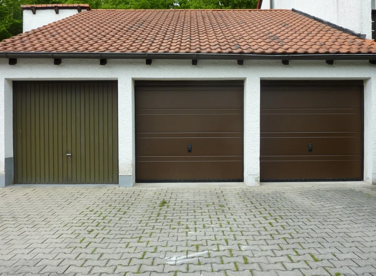 Garagenhof mit drei Toren: links ein altes Schwingtor, daneben zwei neue Sektionaltore
