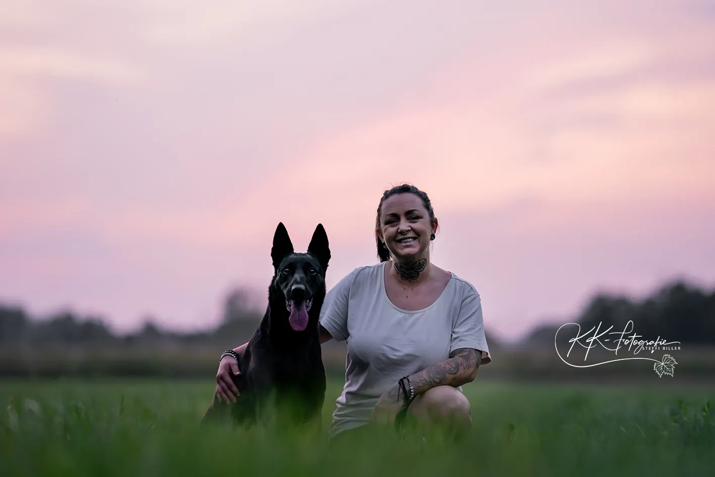 Katha mit ihrem Hund auf einer Wiese im Abendlicht