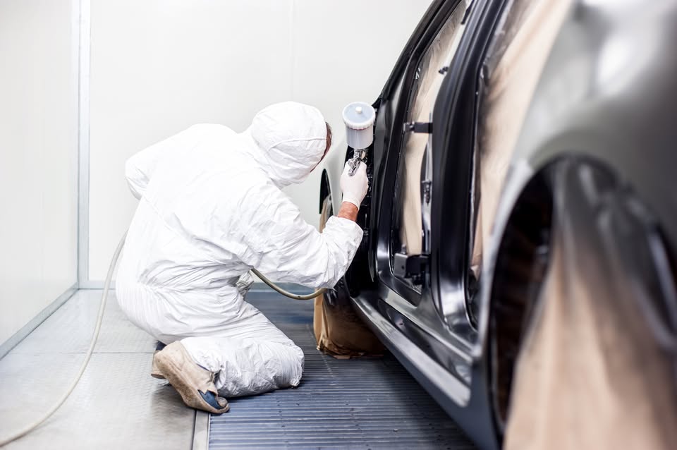 Lackierer bei der Arbeit in der Spritzkabine